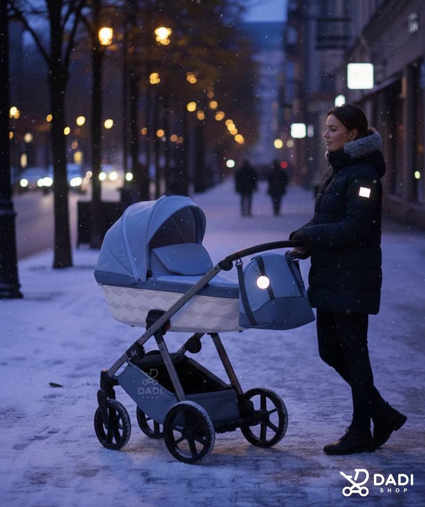 Kobieta spaceruje z wózkiem dziecięcym po zmroku zimą – odblask na ramieniu i zawieszka na wózku dla bezpieczeństwa dziecka.